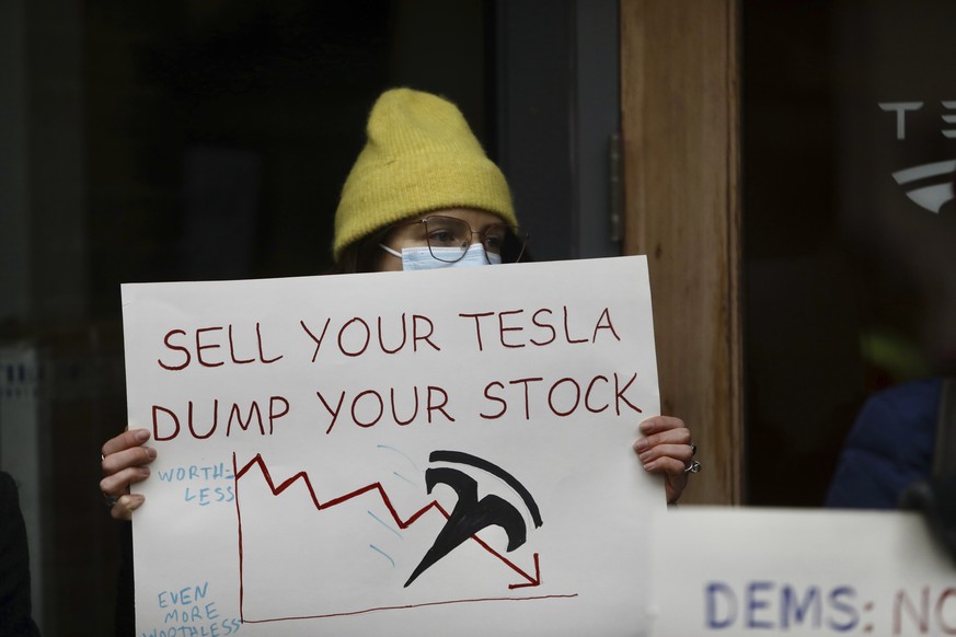 A person protesting Elon Musk&#039;s actions in the Trump administration holds a sign outside a Tesla showroom in Seattle on Thursday, Feb. 13, 2025. (AP Photo/Manuel Valdes)