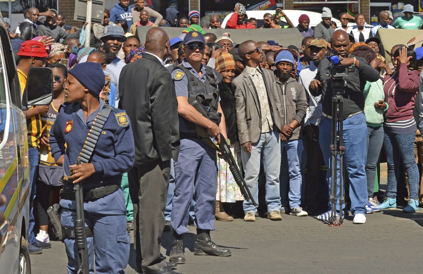 Armed police stand guard outside the magistrates court in Estcourt, South Africa, Monday, Aug.. 21, 2017, where crowds gathered following the brief court appearance of men accused of killing and eatin ...