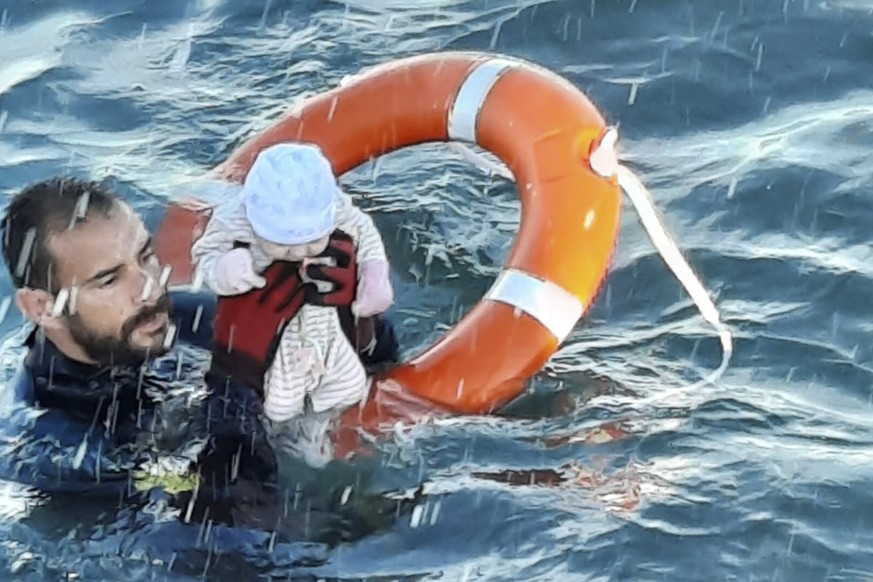 In this photo provided by the Spanish Civil Guard in Ceuta, Spain, on Tuesday May, 18, 2021, a member of the civil guard rescues a baby that was separated from its parents, who were migrants, in the s ...