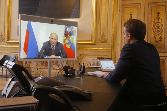 epa08510702 French President Emmanuel Macron listens to Russian President Vladimir Putin during a video at the Elysee Palace in Paris, France, 26 June 2020. Russian President Vladimir Putin holds vide ...