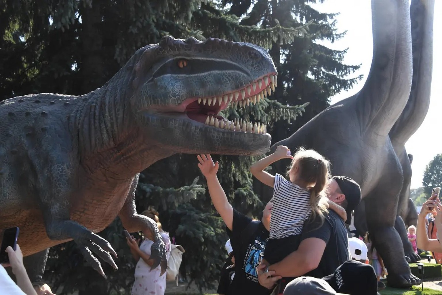 Ein junges Mädchen im Arm ihres Vaters bewundert einen T-Rex in Moskau: Die Saurier-Ausstellung in Russlands Hauptstadt ist Teil der prunkvollen Zukunftsmesse.