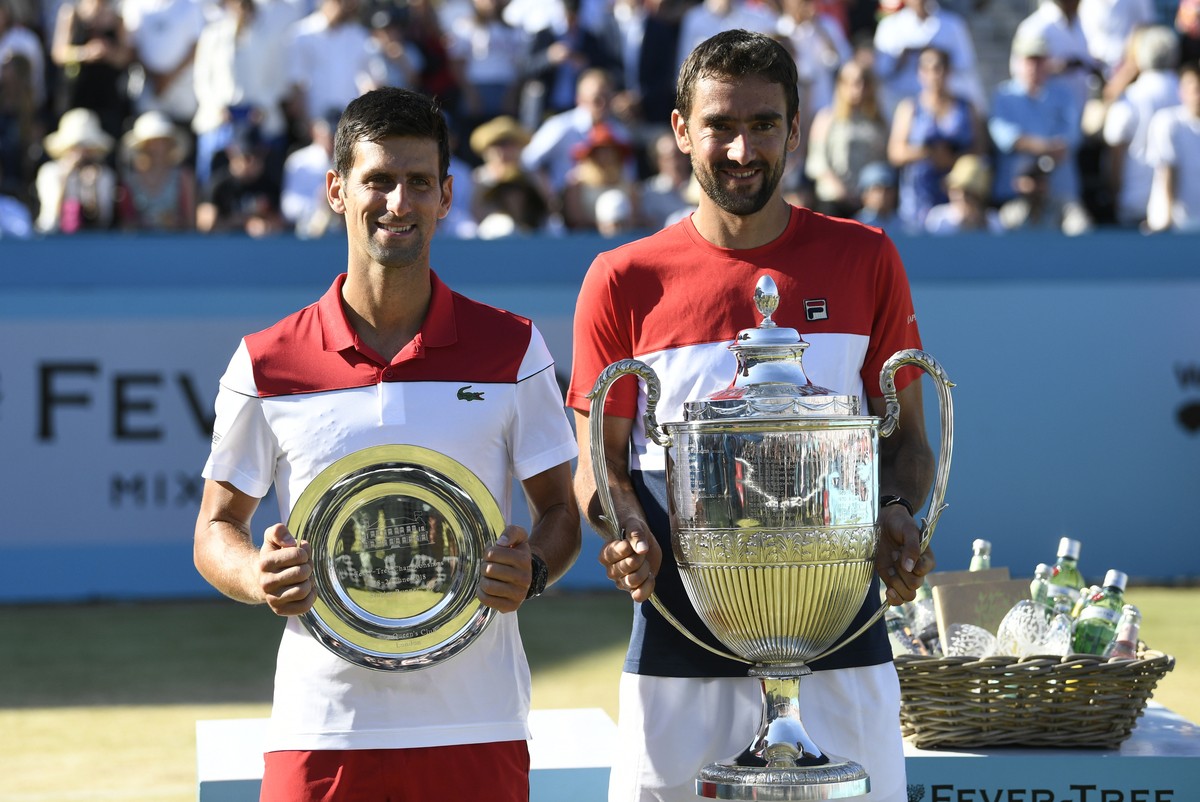 epa06837120 Marin Cilic of Croatia (R) holds his winning trophy next to runner up Novak Djokovic (L) of Serbia after the final match at the Fever Tree Championship at Queen's Club in London, Brit ...