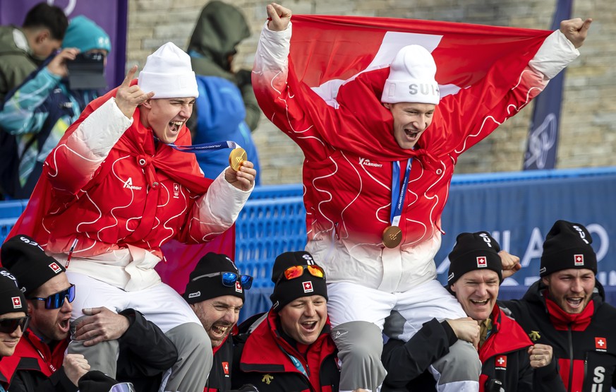 Gold medalist Franjo von Allmen of Switzerland, left, and bronce medalist Marco Odermatt of Switzerland, pose with team after the men's alpine skiing Super-G race at the 2026 Olympic Winter Games ...