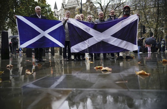 People hold a Scottish flag as they stand outside Britain&#039;s Supreme Court while they wait for the decision by Supreme Court judges to grant or refuse the Scottish Parliament power to hold a refer ...