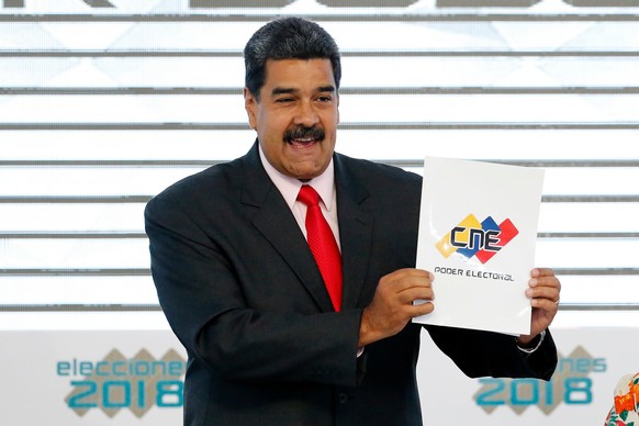 FILE - Venezuela's President Nicolas Maduro holds up the National Electoral Council certificate declaring him the winner of the presidential election, during a ceremony at CNE headquarters in Car ...