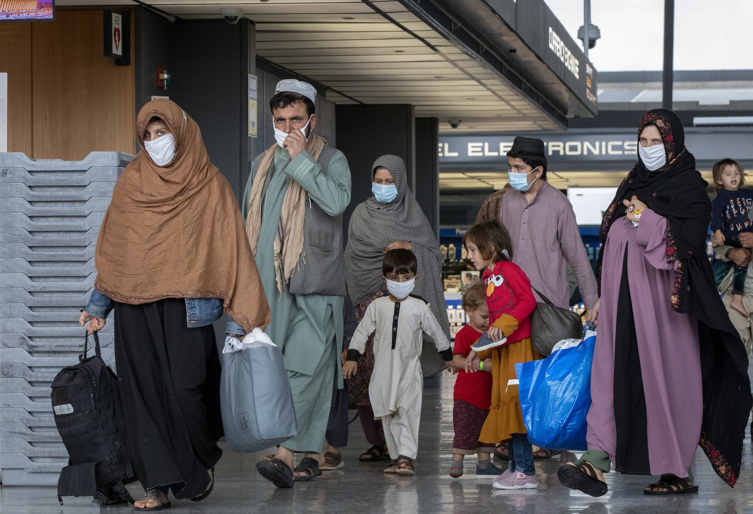 FILE - Families evacuated from Kabul, Afghanistan walk through the terminal to board a bus after they arrived at Washington Dulles International Airport, in Chantilly, Va., Sept. 1, 2021. The Biden ad ...