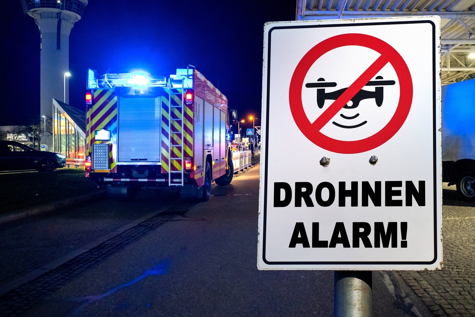 Munich Bavaria, Germany - October 4, 2025: PHOTOMONTAGE, fire department at night with blue light at Munich Airport in Bavaria archive picture with a drone prohibition sign with the lettering: DROHNEN ...