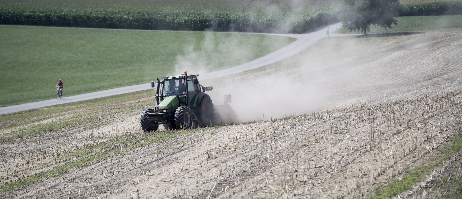 Ein Landwirt faehrt mit einem Traktor ueber ein kuerzlich abgeerntetes Rapsfeld und erzeugt dabei wegen der Trockenheit eine Staubwolke am Donnerstag, 19. Juli 2018 bei Aristau im Kanton Aargau. (KEYS ...