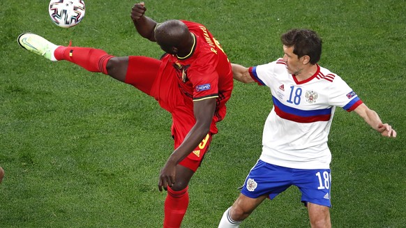 epa09265859 Romelu Lukaku (C) of Belgium in action against Russian players Magomed Ozdoyev (L) and Yuri Zhirkov (R) during the UEFA EURO 2020 group B preliminary round soccer match between  Belgium and Russia in St.Petersburg, Russia, 12 June 2021.  EPA/Anton Vaganov / POOL (RESTRICTIONS: For editorial news reporting purposes only. Images must appear as still images and must not emulate match action video footage. Photographs published in online publications shall have an interval of at least 20 seconds between the posting.)