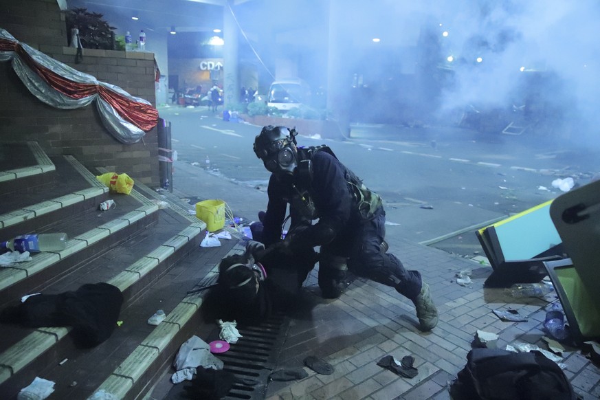 A policeman in riot gear detains a protester outside of Hong Kong Polytechnic University as police storm the campus in Hong Kong, early Monday, Nov. 18, 2019. Fiery explosions were seen early Monday a ...