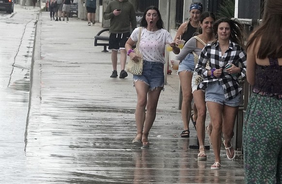 Pedestrians run past a splash zone on the sidewalk of A1A just south of Sunrise Blvd., in Fort Lauderdale, Fla., on Sunday, Jan 16, 2022. A line of thunderstorms caused a tornado warning and flooding  ...