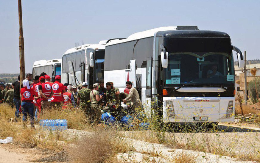 In this photo released by the Syrian official news agency SANA, ﻿Syrian government forces and Syrian Arab Red Crescent oversee the evacuation by buses of opposition fighters and their families from th ...