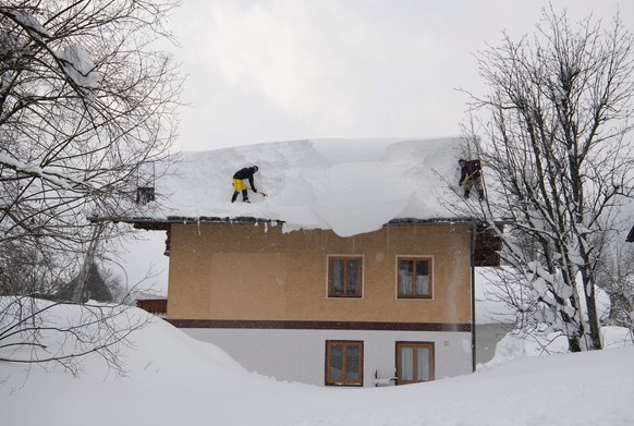epa07269602 Two men try to remove snow from a roof of a house in Filzmoos, Austria, 08 January 2019. Media reports state that many regions in Austria, Germany, Switzerland and northern Italy have been ...