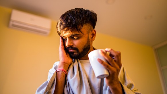 arabian indian man drinking hot lemon dinder masala tea in morning bedroom while feeling cold covered with a blanket. xkwx medical, sickness, sick, cough, problem, epidemic, symptoms, influenza, infec ...