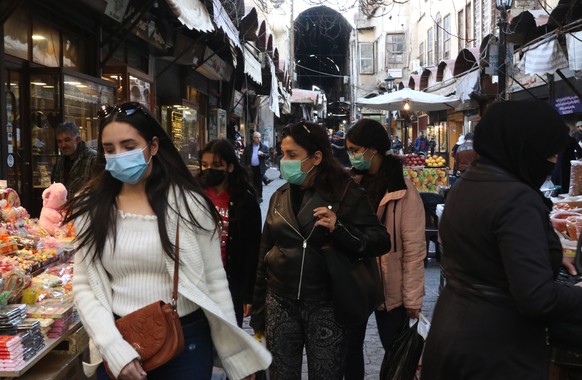 epa09061911 Syrians wearing masks are seen walking on one of the streets of Damascus, Syria, on 8 March 2021. The Presidency of the Syrian Arab Republic has announced that President Bashar al-Assad an ...