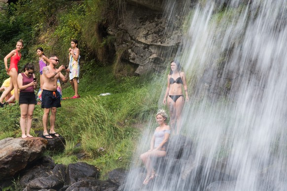 Badende suchen an diesem Hitzetag mit Temperaturen ueber 30 Grad Abkuehlung in den natuerlichen Wasserbecken unter dem Wasserfall Piumogna Wasserfall bei Faido am Mittwoch, 29. Julie 2020. (KEYSTONE/T ...