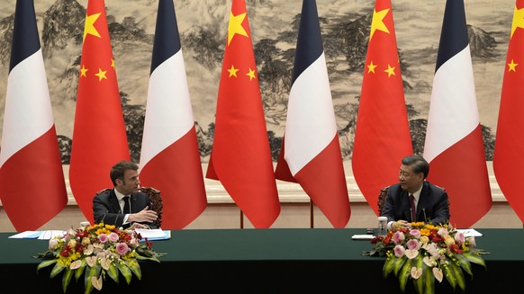 epa10561394 French President Emmanuel Macron (L) looks over to Chinese President Xi Jinping during a joint meeting of the press at the Great Hall of the People in Beijing, China, 06 April 2023. EPA/Ng ...