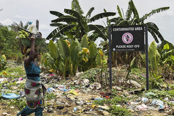 epa05203261 A Nigerian woman walks past a sign on polluted land warning of contamination in the Ogale community in the oil rich Niger Delta, Nigeria, 09 March 2016. Oil company Shell is being sued in  ...