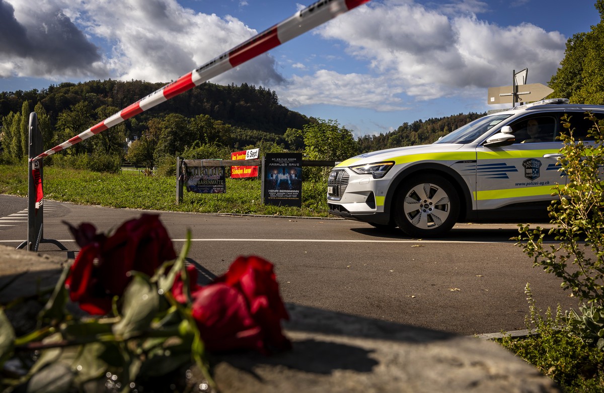 KEYPIX - A police car drives past flowers that have been laid down in a near the Schachen horse racing track, the site of a rave party, following a deadly shooting incident on Sunday, in Aarau Switzer ...