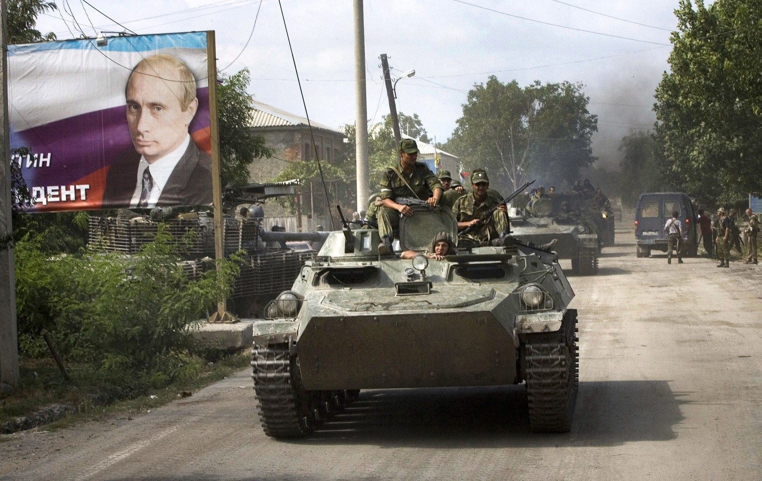 FILE - Ossetian soldiers on top of an armored personnel carrier enter Tskhinvali, the capital of Georgian breakaway enclave of South Ossetia on Aug. 11, 2008, next to a giant portrait of Prime Ministe ...