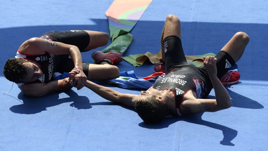 Gold medalist Britain&#039;s Alistair Brownlee, left, and his brother, silver medalist Jonathan Brownlee celebrate as they cross the finish line the men’s Triathlon in Fort Copacabana at the Rio 2016  ...