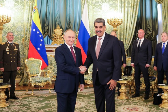 epa12081083 A handout photo made available by the Miraflores Palace Press Office shows Venezuelan President Nicolas Maduro (R) greeting his Russian counterpart Vladimir Putin at the Kremlin in Moscow, ...