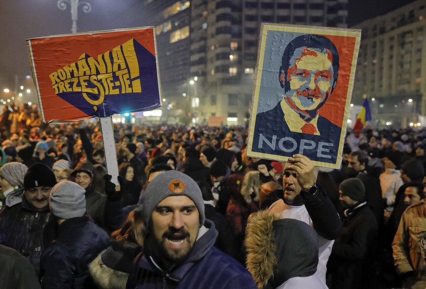 People hold posters depicting the leader of the ruling Social Democratic party Liviu Dragnea, the other reading &quot;Romania-Wake Up&quot; during a protest in Bucharest, Romania, early Wednesday, Feb ...