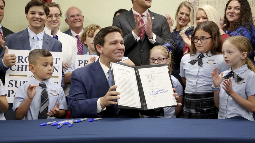 Florida Gov. Ron DeSantis displays the signed Parental Rights in Education, aka the Don&#039;t Say Gay bill, flanked by elementary school students during a news conference on Monday, March 28, 2022, a ...