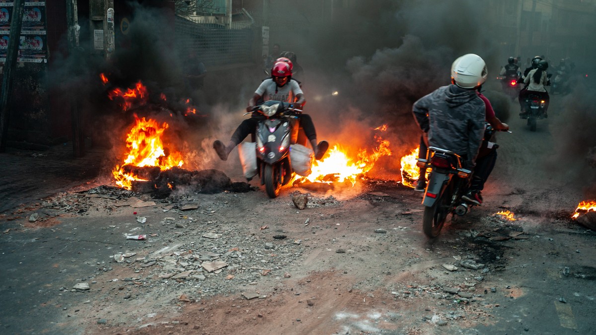 KEYPIX - epa12405381 People ride scooters over burning tires set on fire by protesters during a rally in Antananarivo, Madagascar, 25 September 2025. Police fired tear gas and rubber bullets to disper ...