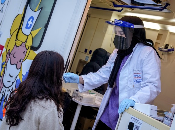 A medical worker carries out a Corona rapid test in a test van in Frankfurt, Germany, Thursday, Nov. 11, 2021. Numbers of Corona infections are steadily rising again. (AP Photo/Michael Probst)