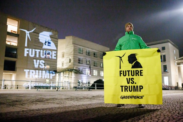 epaselect epa11843184 An activist displays a banner reading &#039;Future vs. Trump - Greenpeace&#039; as he stands at the US embassy in Berlin, Germany, 21 January 2025. Greenpeace staged a protest by ...