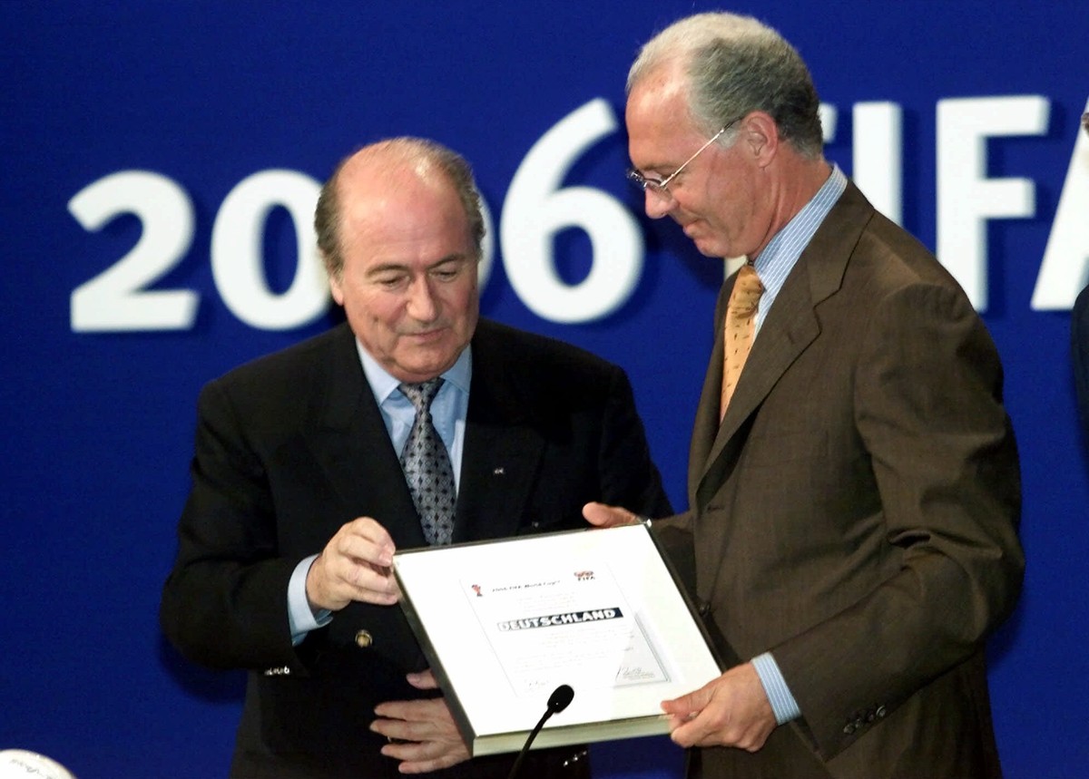 FILE - In this July 6, 2000 file picture FIFA president Joseph Blatter, left, hands over the World Cup documents to Franz Beckenbauer of the German delegation in Zurich, Switzerland, after soccer' ...