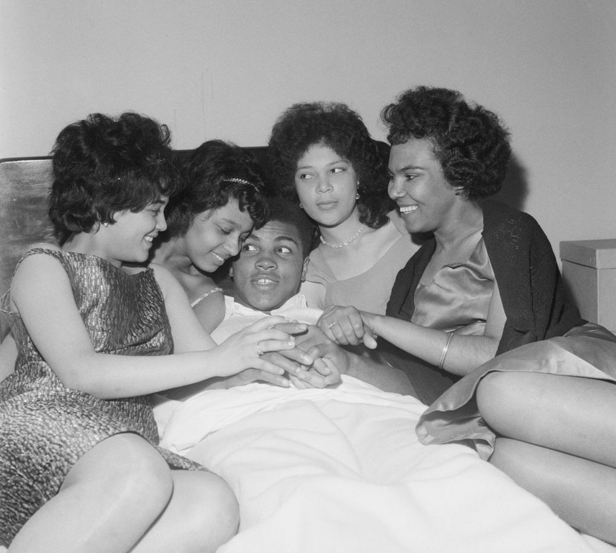 American Heavyweight boxer, Cassius Clay (later Muhammad Ali, 1942 - 2016), relaxing in his London hotel room with friends, Brenda Howell, Norma Lindo, Kathleen O"u2019Flaherty and Hallie Hemming ...