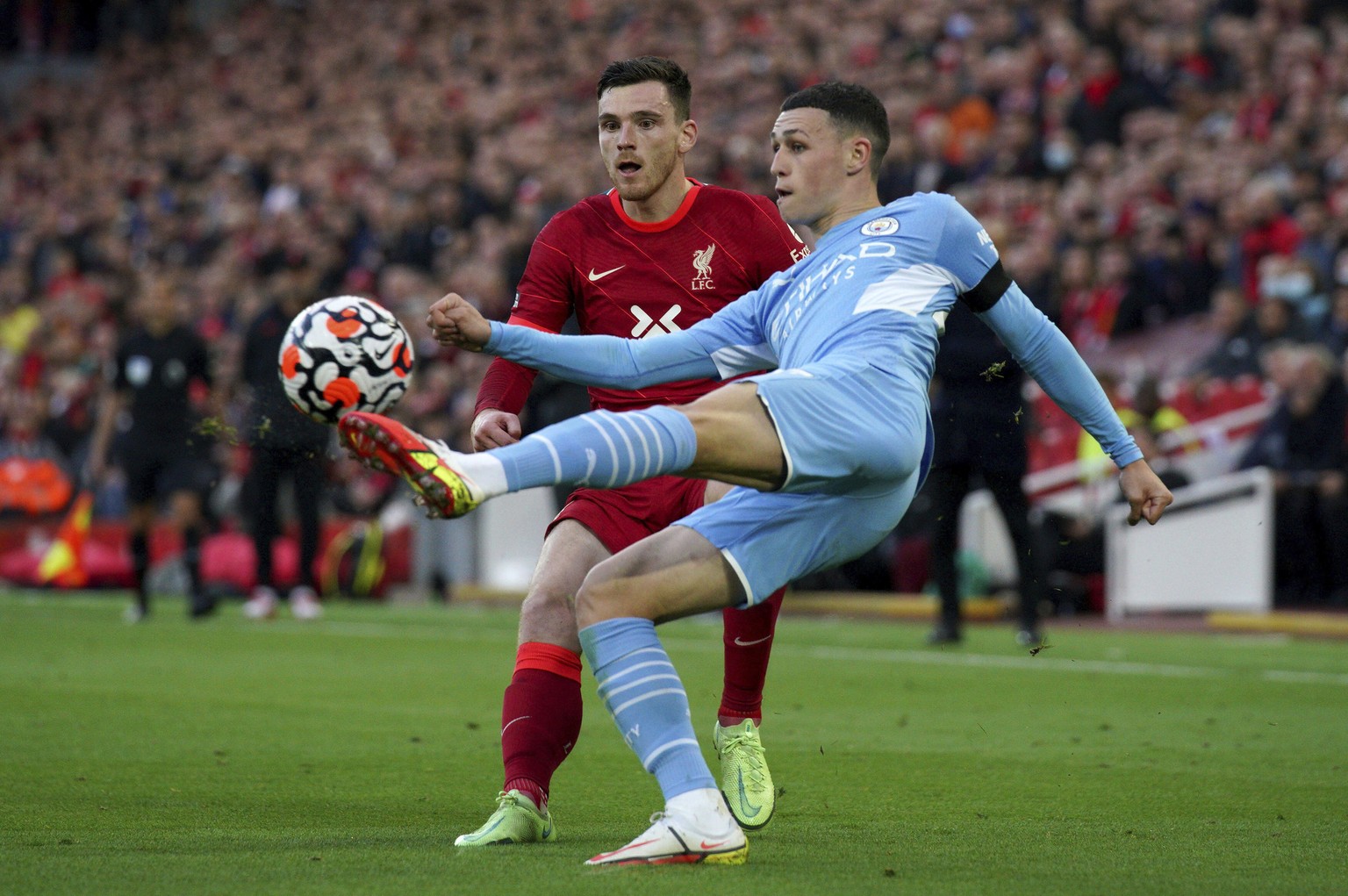 Manchester City&#039;s Phil Foden, right, kicks the ball past Liverpool&#039;s Andrew Robertson during the English Premier League soccer match between Liverpool and Manchester City at Anfield, Liverpo ...