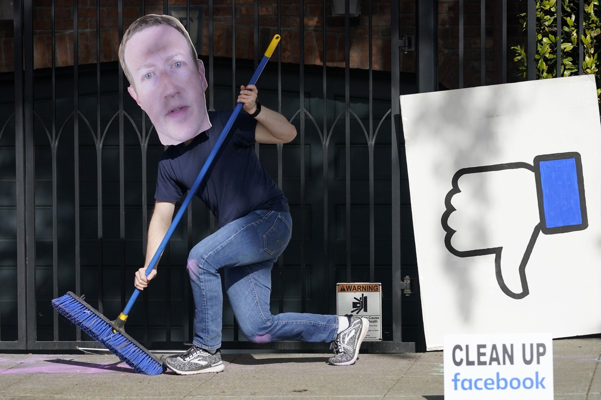 A man who did not give his name wears a mask of Facebook CEO Mark Zuckerberg as he and others demonstrate outside of Zuckerberg's home to protest what they say is Facebook spreading disinformatio ...
