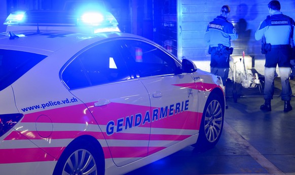 [Editor&#039;s note: photo mise-en-scene] A patrol of the cantonal police of Vaud searches a site, in the background, while their car with blue lights switched on is seen in the foreground, photograph ...