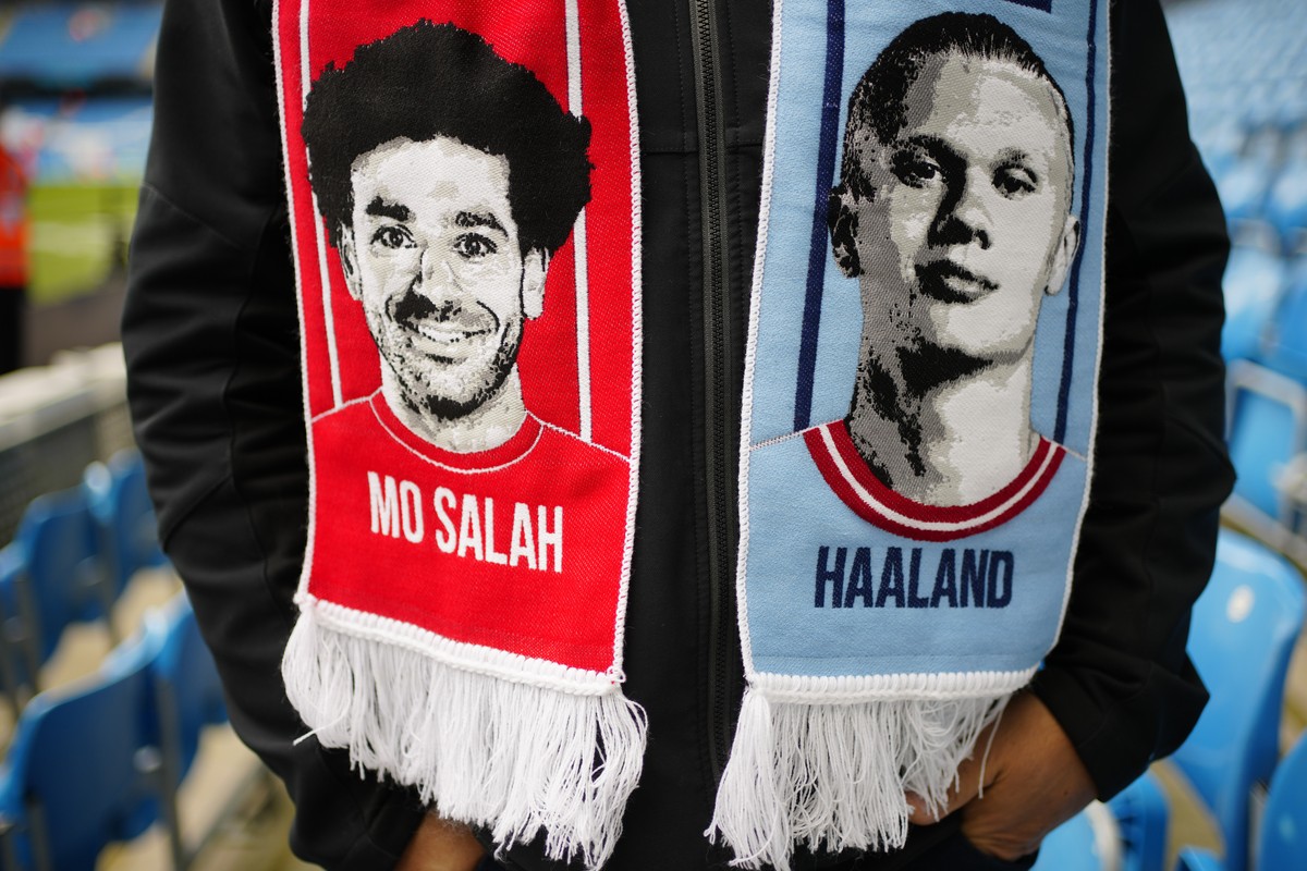 A fan wears a half and half scarf featuring Liverpool's Mohamed Salah and Manchester City's Erling Haaland prior to the English Premier League soccer match between Manchester City and Liverp ...