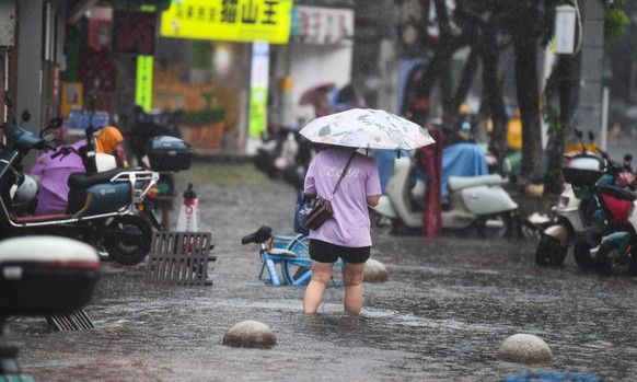 epa12249374 A pedestrian wades through a flooded area in Haikou, Hainan Province, China, 20 July 2025. Typhoon Wipha, the sixth typhoon of the year, made landfall near Jiangmen City in south China&#03 ...