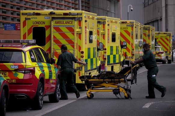Paramedics push a trolley next to a line of ambulances outside the Royal London Hospital in the Whitechapel area of east London, Thursday, Jan. 6, 2022. Health authorities across the U.K. simplified COVID-19 testing requirements on Wednesday, a move designed to cut isolation times for many people and that may ease the staffing shortages that are hitting public services amid an omicron-fueled surge in coronavirus infections. A string of National Health Service local organizations have declared &quot;critical incidents&quot; in recent days amid staff shortages. (AP Photo/Matt Dunham)