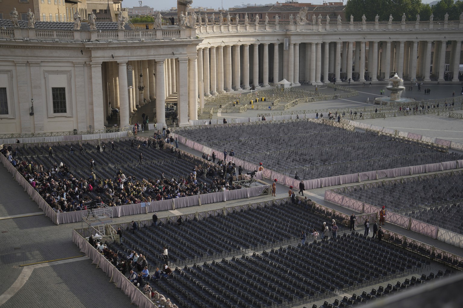 People gather in St. Peter's Square as they await the arrival of the body of Pope Francis, who will lie in state at St. Peter�s Basilica for three days, at the Vatican, Wednesday, April 23, 2025. ...