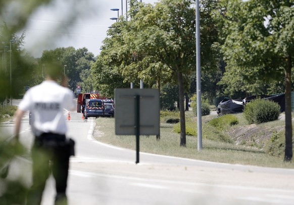 A police officers park outside the plant where an attack took place, Friday, June 26, 2015 in Saint-Quentin-Fallavier, southeast of Lyon, France. French authorities say one person has been beheaded in ...