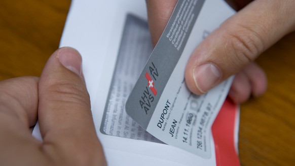 A man takes a prototype of the new insurance certificate of the AHV-IV (AHV: Federal old-age and bereaved people insurance/IV: Disabled people insurance) with the name of the insured party, the date o ...