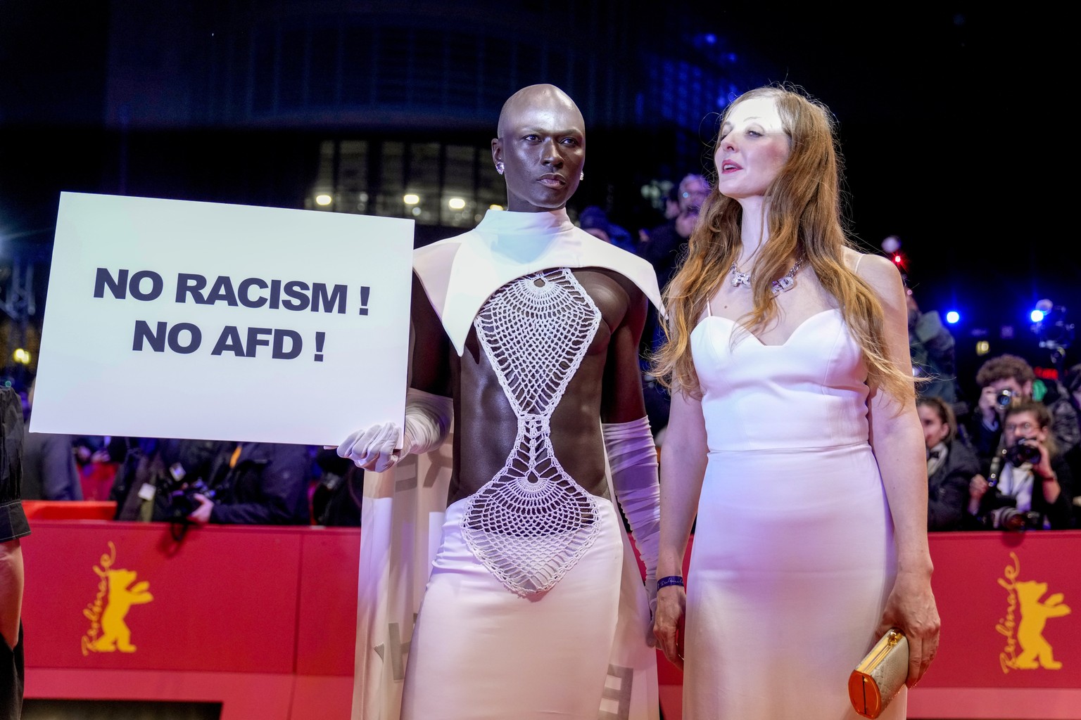 A person holds a sign reading &quot; no racism, no AFD&quot; on the red carpet outside the Berlinale Palast during the opening of the International Film Festival, Berlinale,in Berlin, Thursday, Feb. 1 ...