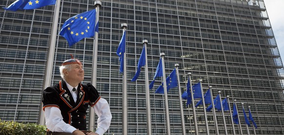 Flags of the European Union wave in front of the European Commission building in Brussels, June 8, 2011, while &quot;Mister Swiss&quot;, dressed in a traditional Swiss costume, looks on. He is on his  ...