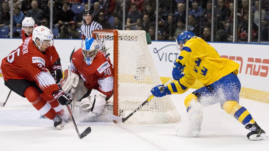 CORRECTS DATE - Sweden&#039;s Fabian Zetterlund (28) tries to get a shot on Switzerland goalie Luca Hollenstein as Switzerland&#039;s David Aebischer looks on during the first period of a world junior ...