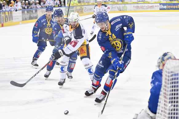 Davos&#039; Marc Wieser, links, und Davos&#039; Tomas Kundratek, rechts, gegen Zugs David McIntyre, Mitte, beim Eishockey-Qualifikationsspiel der National League A zwischen dem HC Davos und dem EV Zug ...