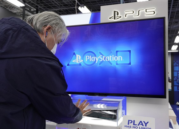 epa08814966 A man looks at the new Sony PlayStation 5 (PS5) console installed inside a plastic case at a discount chain store in Tokyo, Japan, 12 November 2020. Sony Interactive Entertainment Inc. lau ...