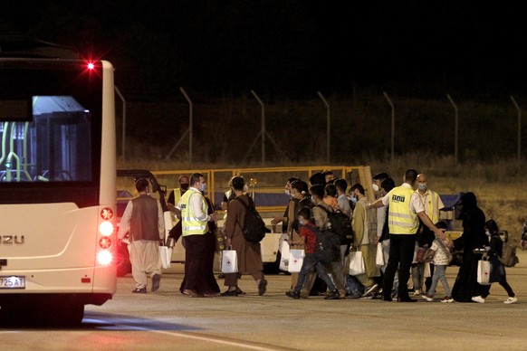 Afghan evacuees are directed to buses after their arrival by a plane at Skopje International Airport, North Macedonia, late Monday, Aug. 30, 2021. A first group of 149 Afghan evacuees landed late Mond ...