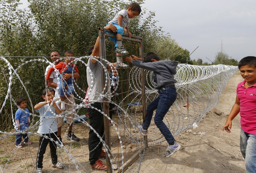Syrian Kurdish migrants climb over the fence on the Hungarian-Serbian border near Asotthalom, Hungary August 25, 2015. Hungary&#039;s government has started to construct a 175-km-long (110-mile-long)  ...