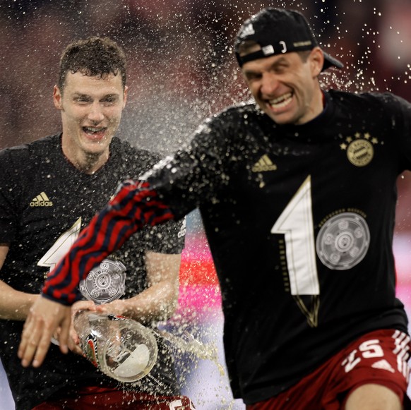 epa09904957 Bayern&#039;s Benjamin Pavard (L) and Thomas Mueller (R) celebrate the tenth consecutive Bundesliga title, after winning the German Bundesliga soccer match between FC Bayern Muenchen and B ...